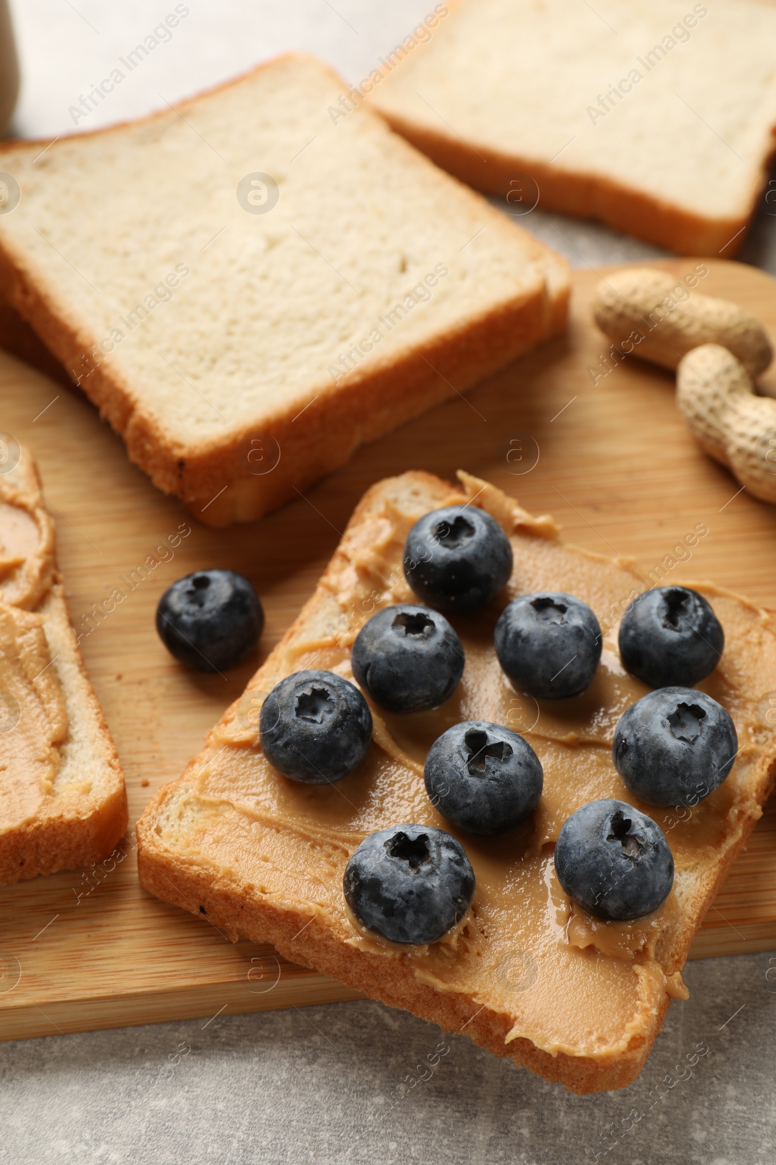 Photo of Tasty peanut butter sandwich with fresh blueberries on table, closeup