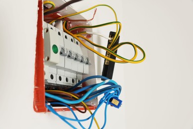 Photo of Switchboard with different cables on white wall. Installation of electrical wiring