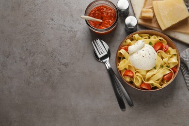Photo of Bowl of delicious pasta with burrata and tomatoes served on grey table, flat lay. Space for text
