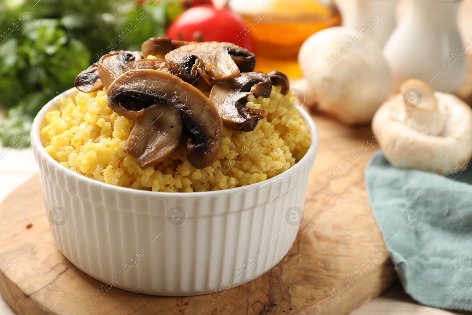 Photo of Tasty millet porridge and mushrooms in bowl on table, closeup