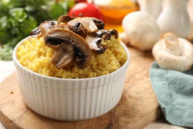 Photo of Tasty millet porridge and mushrooms in bowl on table, closeup