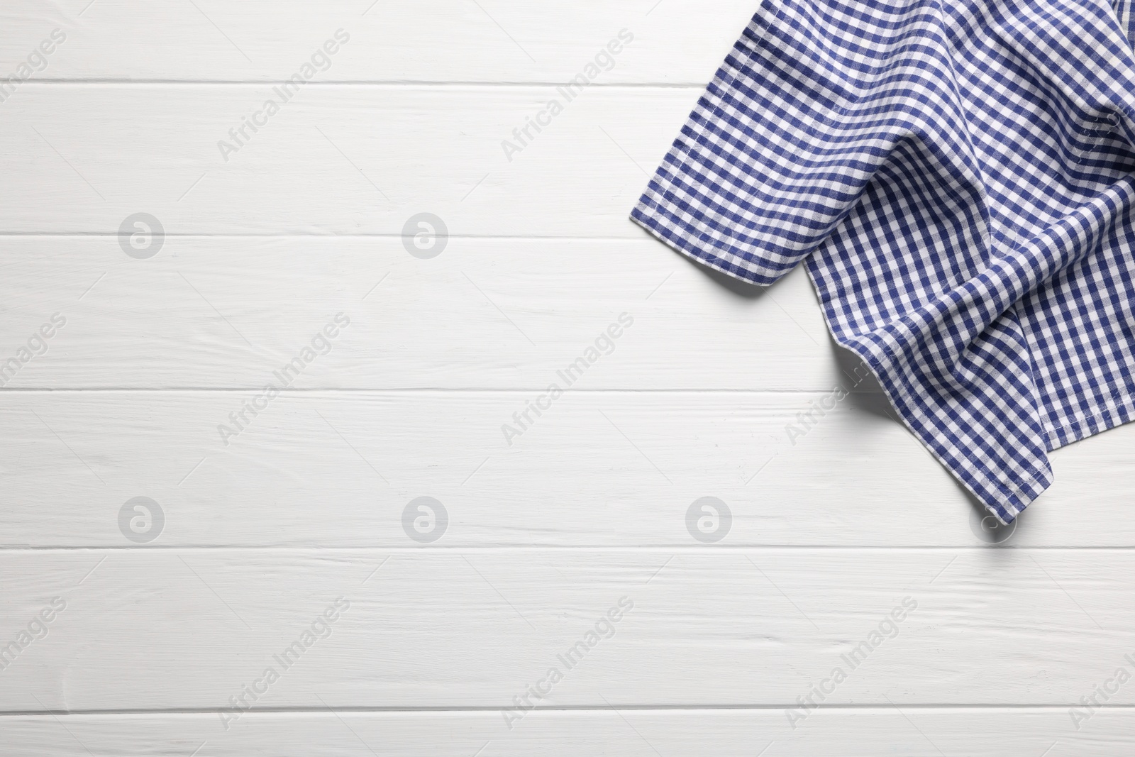 Photo of Blue checkered tablecloth on wooden table, top view. Space for text