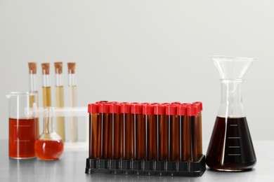 Photo of Different laboratory glassware with brown liquids on table against light background