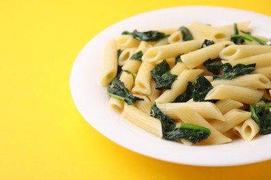 Photo of Tasty pasta with spinach on yellow table, closeup