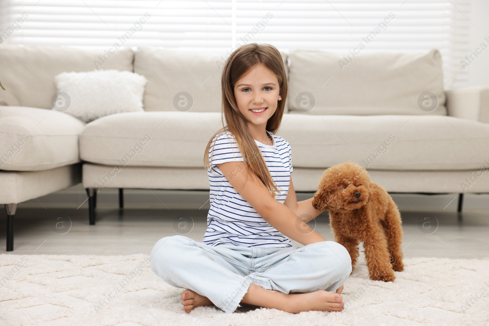 Photo of Little child with cute puppy on carpet at home. Lovely pet