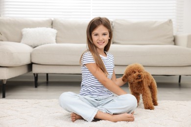 Little child with cute puppy on carpet at home. Lovely pet