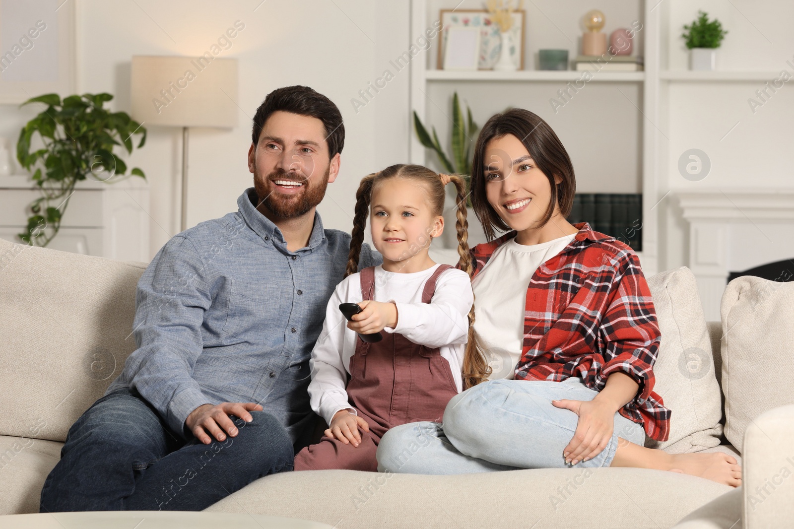 Photo of Happy family watching TV on sofa at home