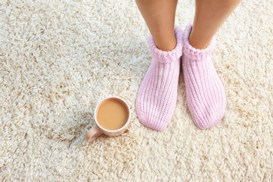 Photo of Woman and cup of coffee on carpet, closeup view with space for text. Floor heating