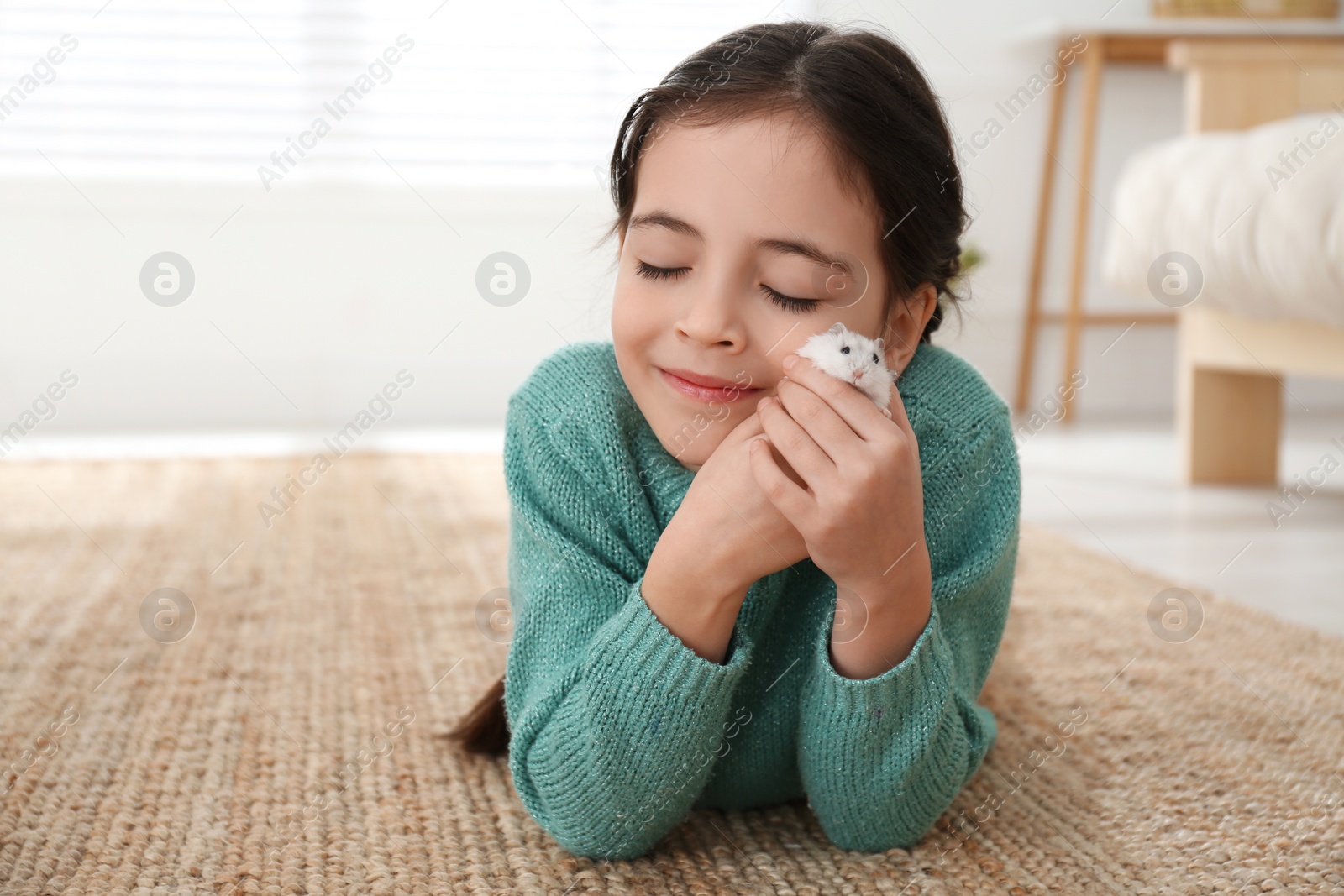 Photo of Little girl with cute hamster at home