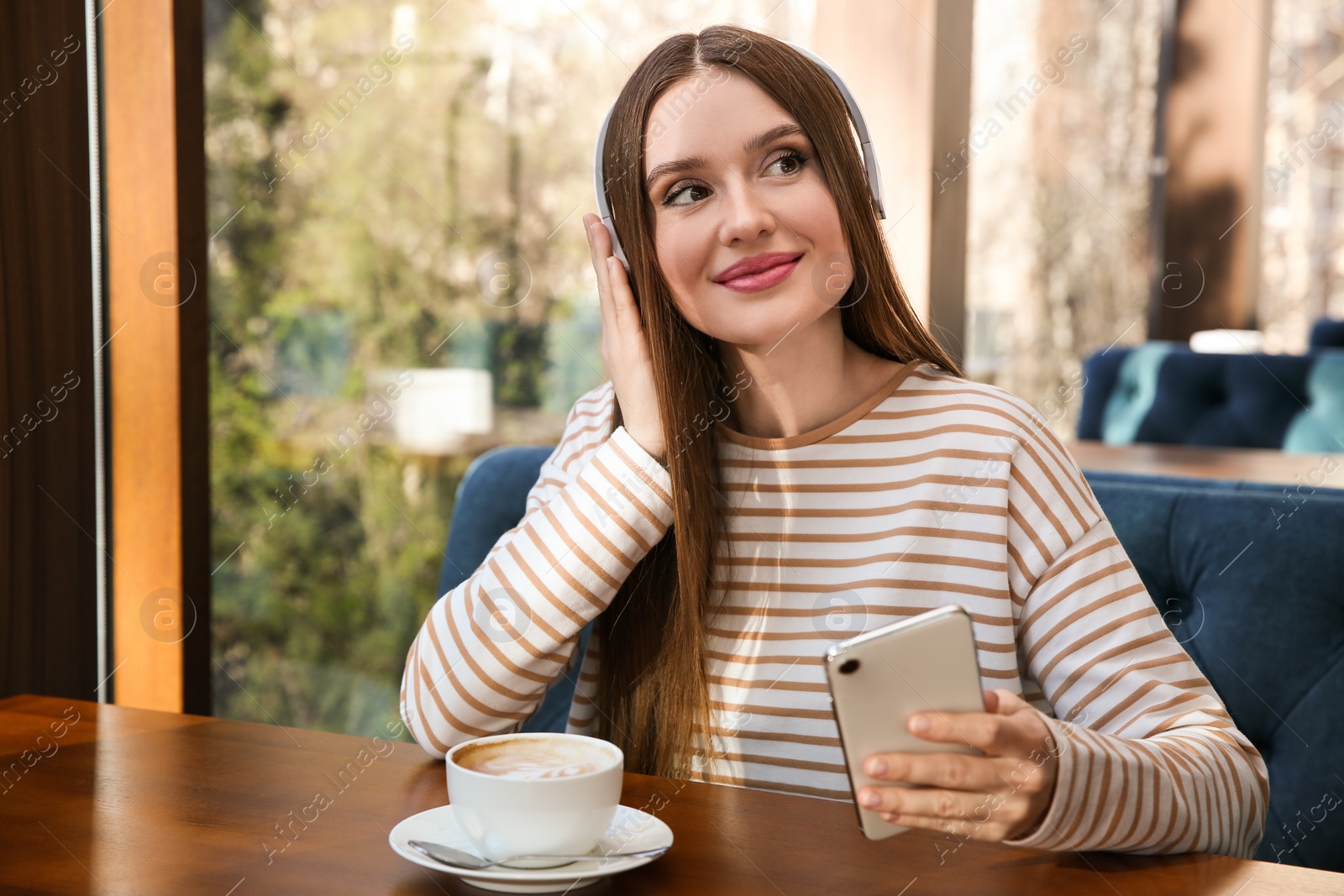 Photo of Woman listening to audiobook at table in cafe