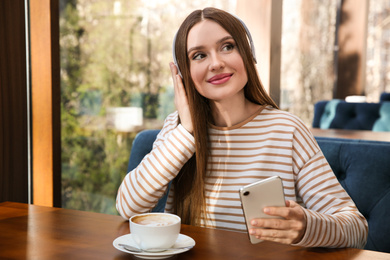 Woman listening to audiobook at table in cafe