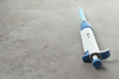 Photo of Laboratory analysis. Micropipette with liquid on grey table, closeup. Space for text