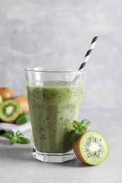 Photo of Delicious kiwi smoothie and fresh fruits on light table