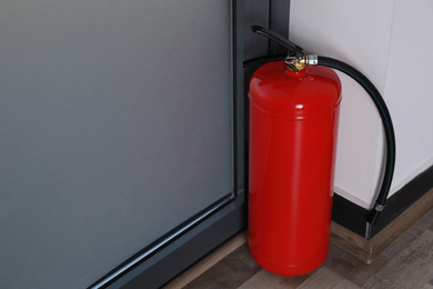 Photo of Fire extinguisher near door indoors. Space for text