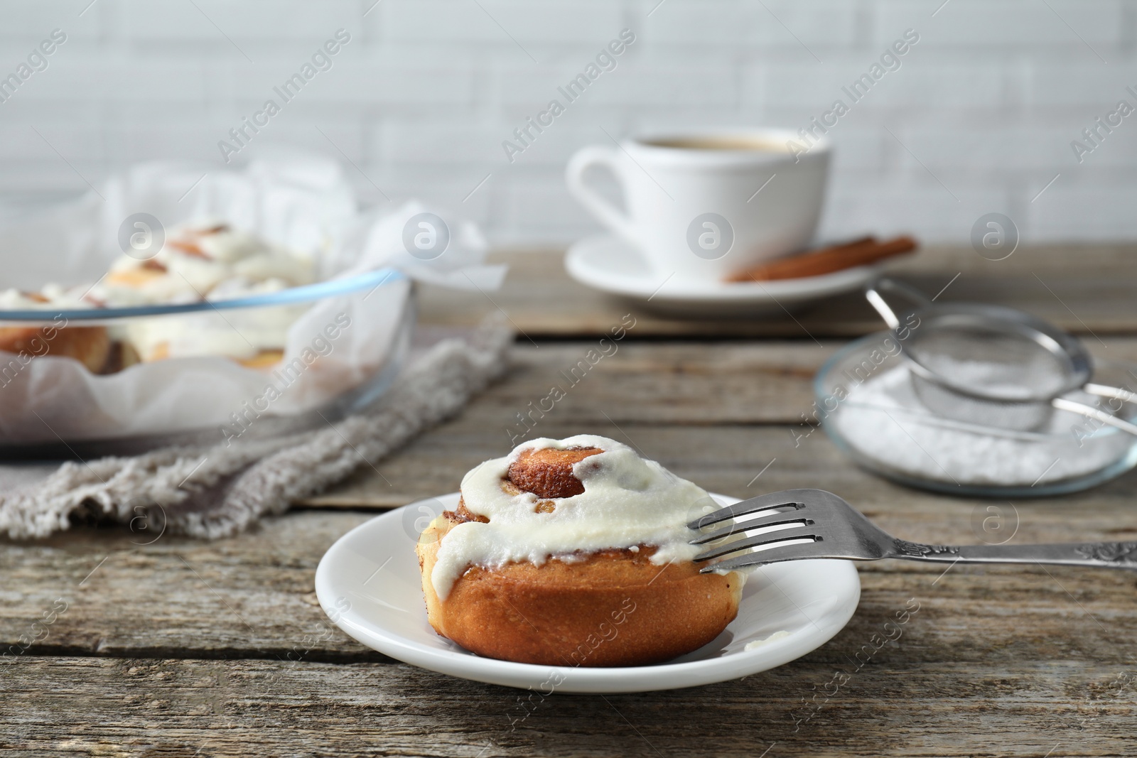 Photo of Tasty cinnamon roll with cream on wooden table. Space for text