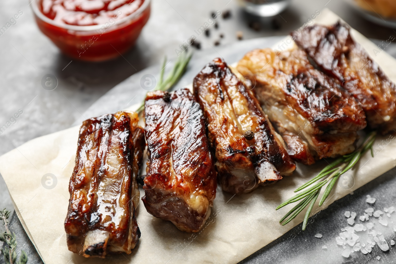 Photo of Delicious grilled ribs with rosemary on table, closeup