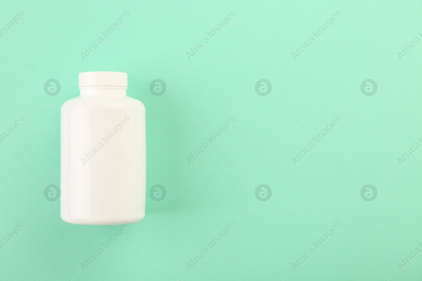 Photo of Blank white pill bottle on turquoise background, top view. Space for text