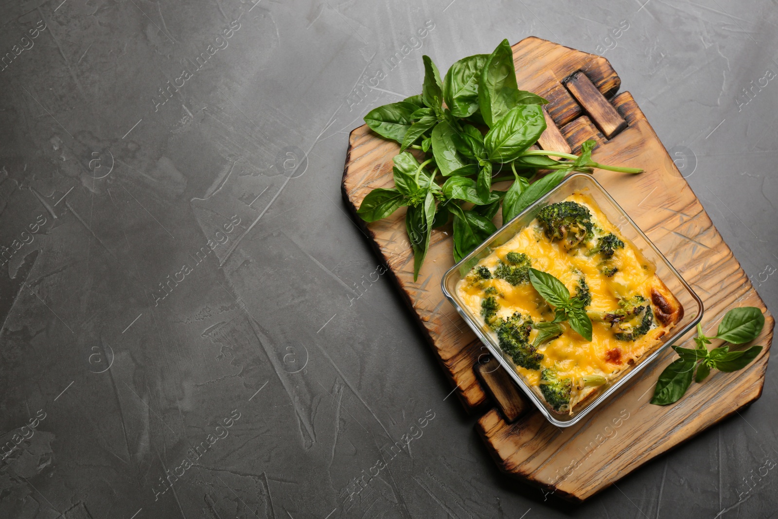 Photo of Tasty broccoli casserole in baking dish on grey table, top view. Space for text