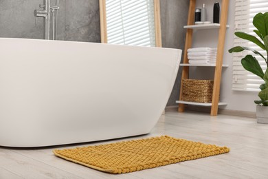 Soft yellow bath mat on floor in bathroom