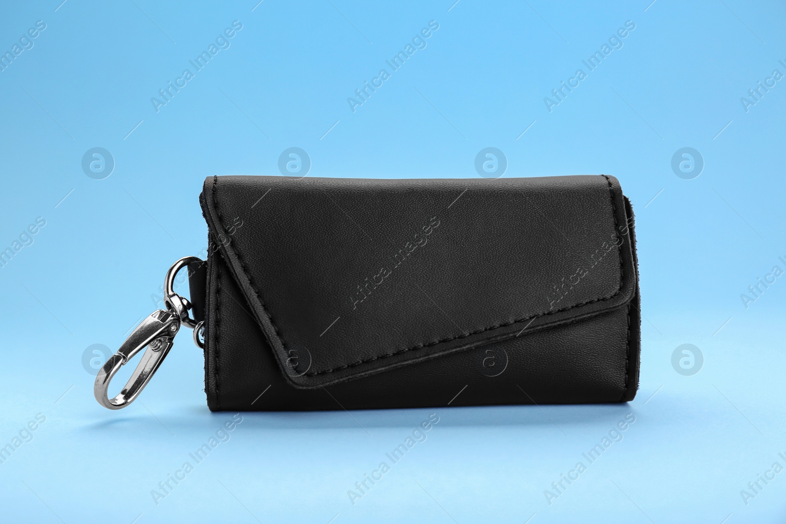 Photo of Stylish leather keys holder on light blue background