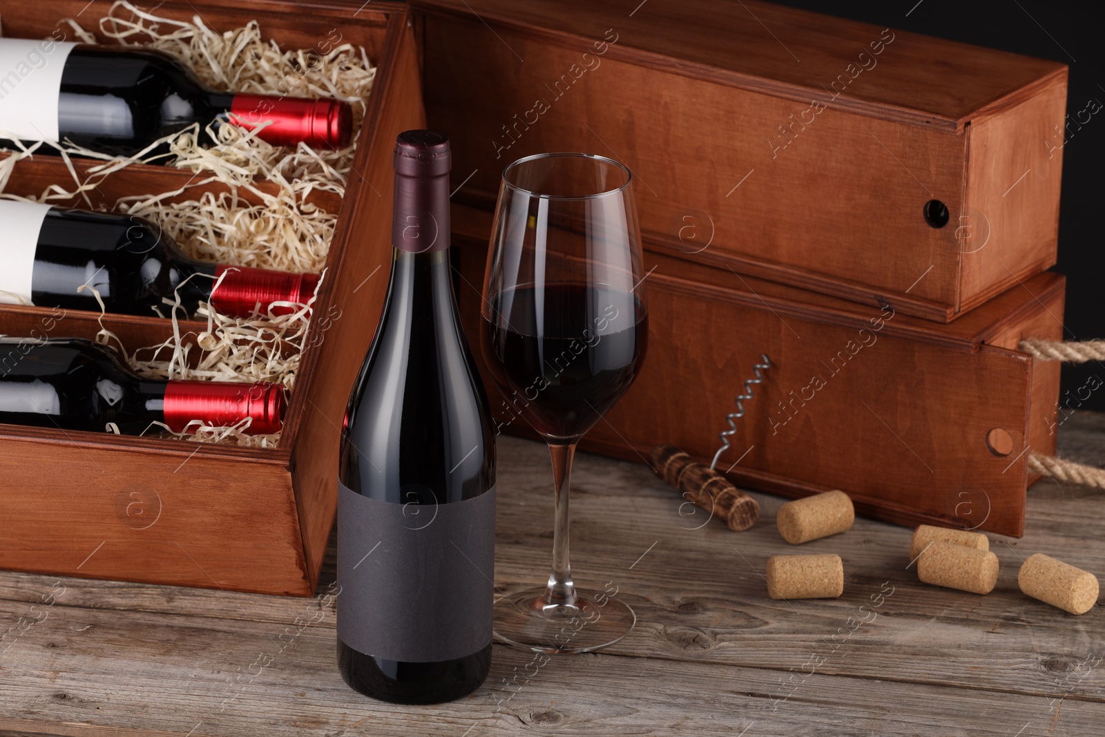 Photo of Box with wine bottles, glass, corks and corkscrew on wooden table