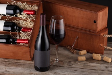 Box with wine bottles, glass, corks and corkscrew on wooden table