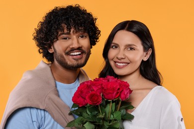 International dating. Happy couple with bouquet of roses on yellow background