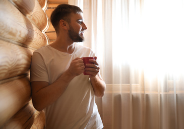 Man with drink near window indoors. Lazy morning