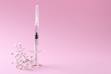 Photo of Cosmetology. Medical syringe and gypsophila on pink background, space for text
