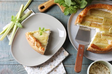 Freshly baked rhubarb pie and stalks on grey wooden table, flat lay