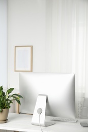 Photo of Office interior with houseplant and computer monitor on table