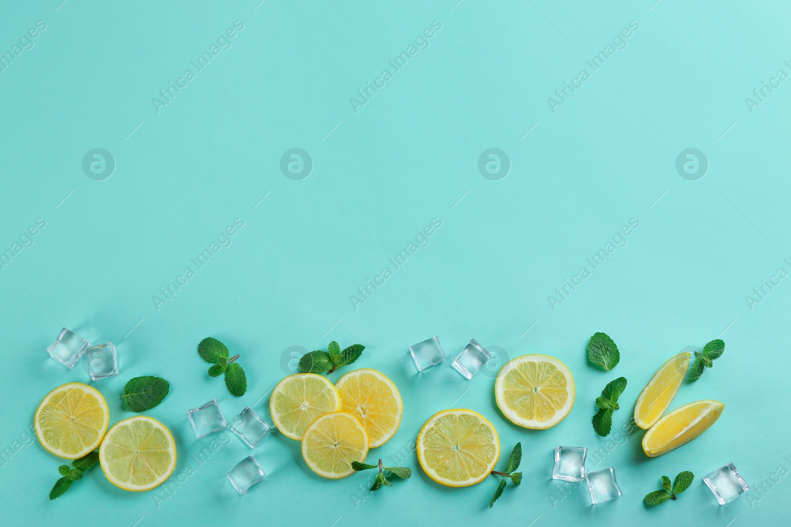 Photo of Lemonade layout with juicy lemon slices, mint and ice cubes on turquoise background, top view. Space for text