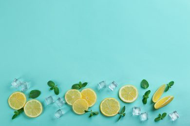 Photo of Lemonade layout with juicy lemon slices, mint and ice cubes on turquoise background, top view. Space for text