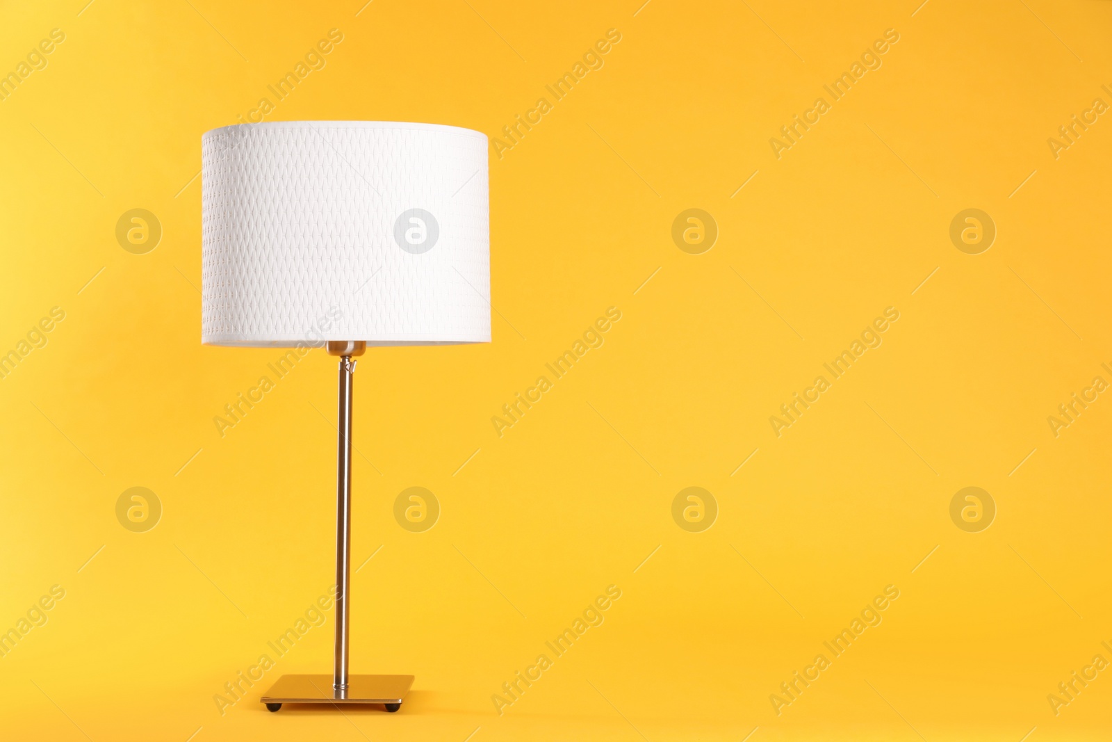 Photo of Stylish new night lamp on yellow background. Space for text