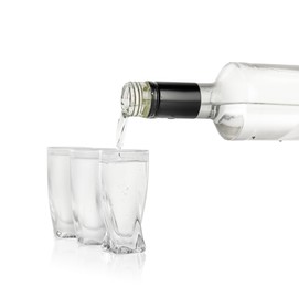 Pouring vodka from bottle in glass on white background