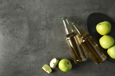 Photo of Delicious cider, whole and cut green apples on gray table, flat lay. Space for text