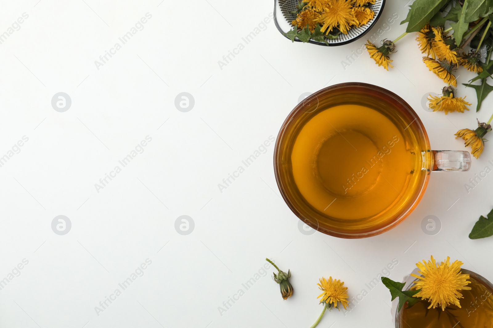 Photo of Delicious fresh tea and beautiful dandelion flowers on white background, top view. Space for text