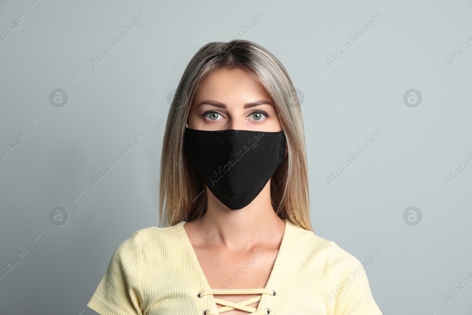 Photo of Young woman in protective face mask on light grey background