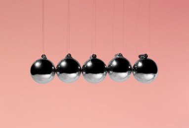 Photo of Newton's cradle on pink background. Physics law of energy conservation