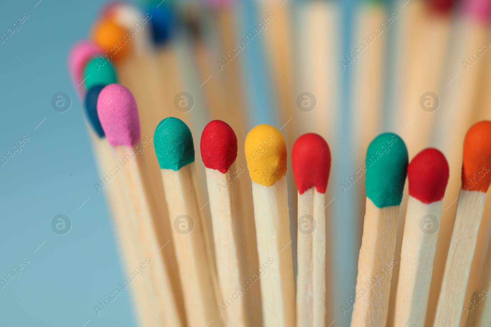 Photo of Matches with colorful heads on light blue background, closeup