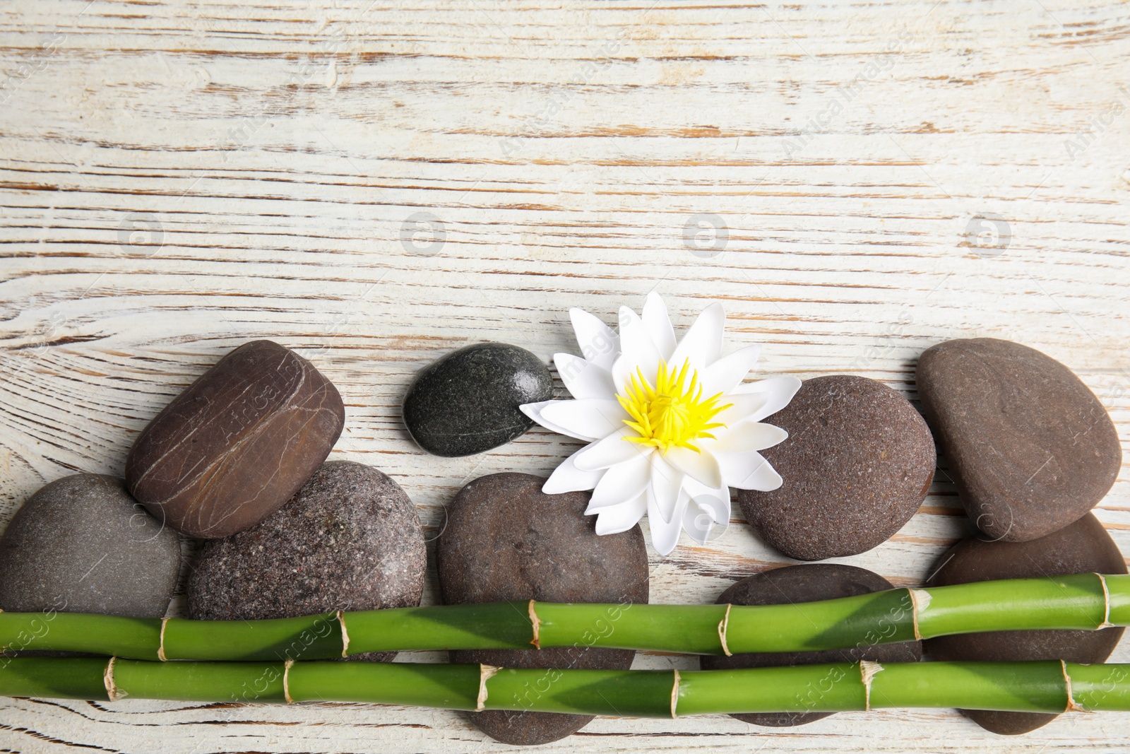 Photo of Stones, bamboo, lotus flower and space for text on white wooden background, flat lay. Zen lifestyle