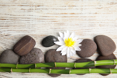 Stones, bamboo, lotus flower and space for text on white wooden background, flat lay. Zen lifestyle