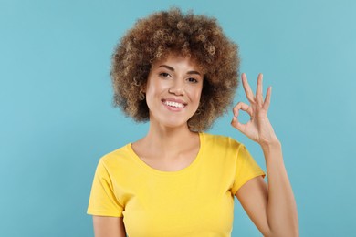 Photo of Woman with clean teeth smiling and showing OK gesture on light blue background