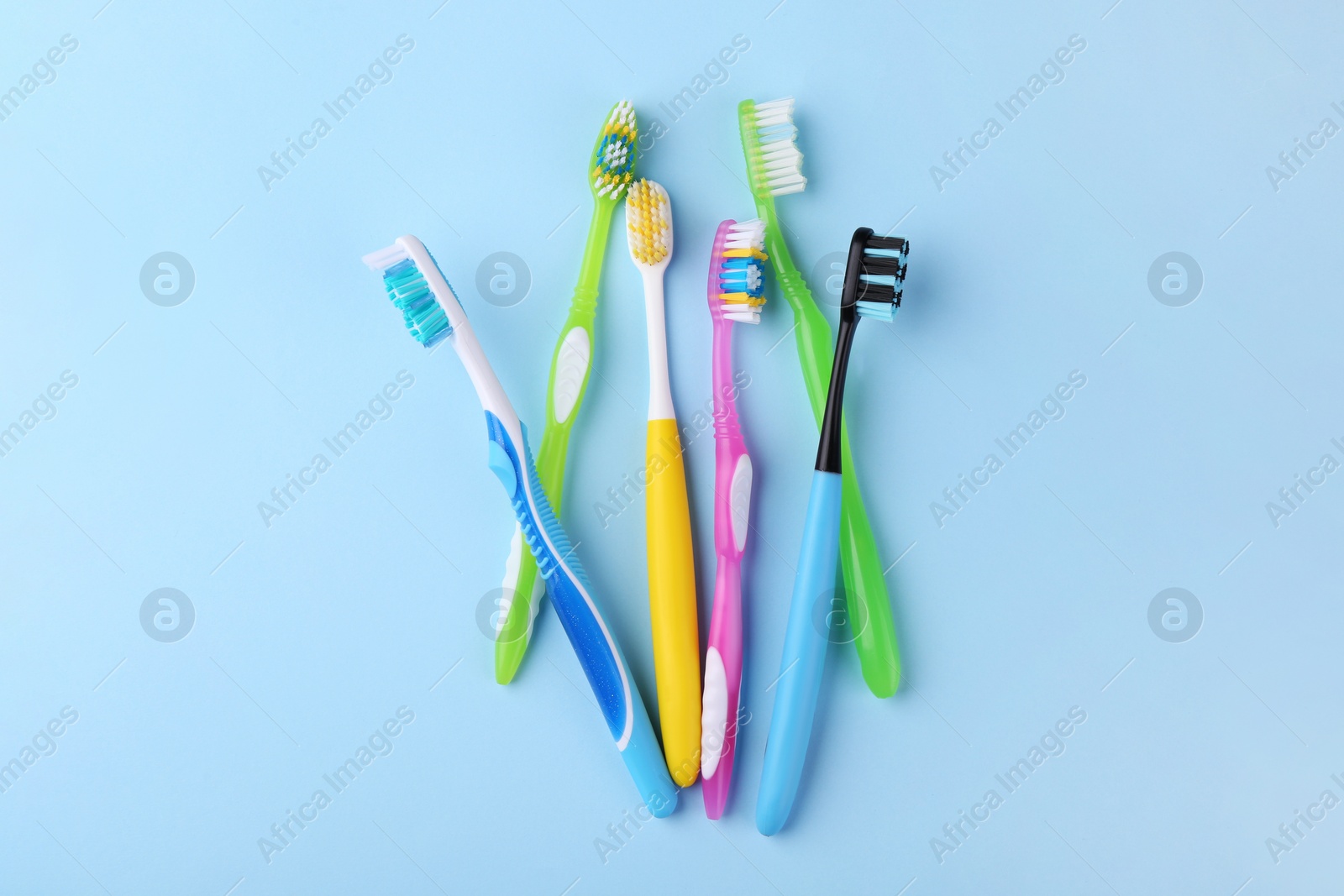 Photo of Many different toothbrushes on light blue background, flat lay