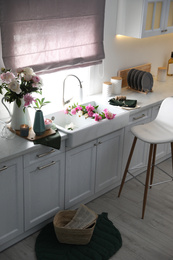 Photo of Beautiful kitchen interior with stylish furniture and fresh peonies