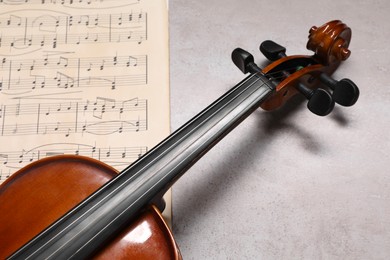 Violin and music sheets on grey table, closeup