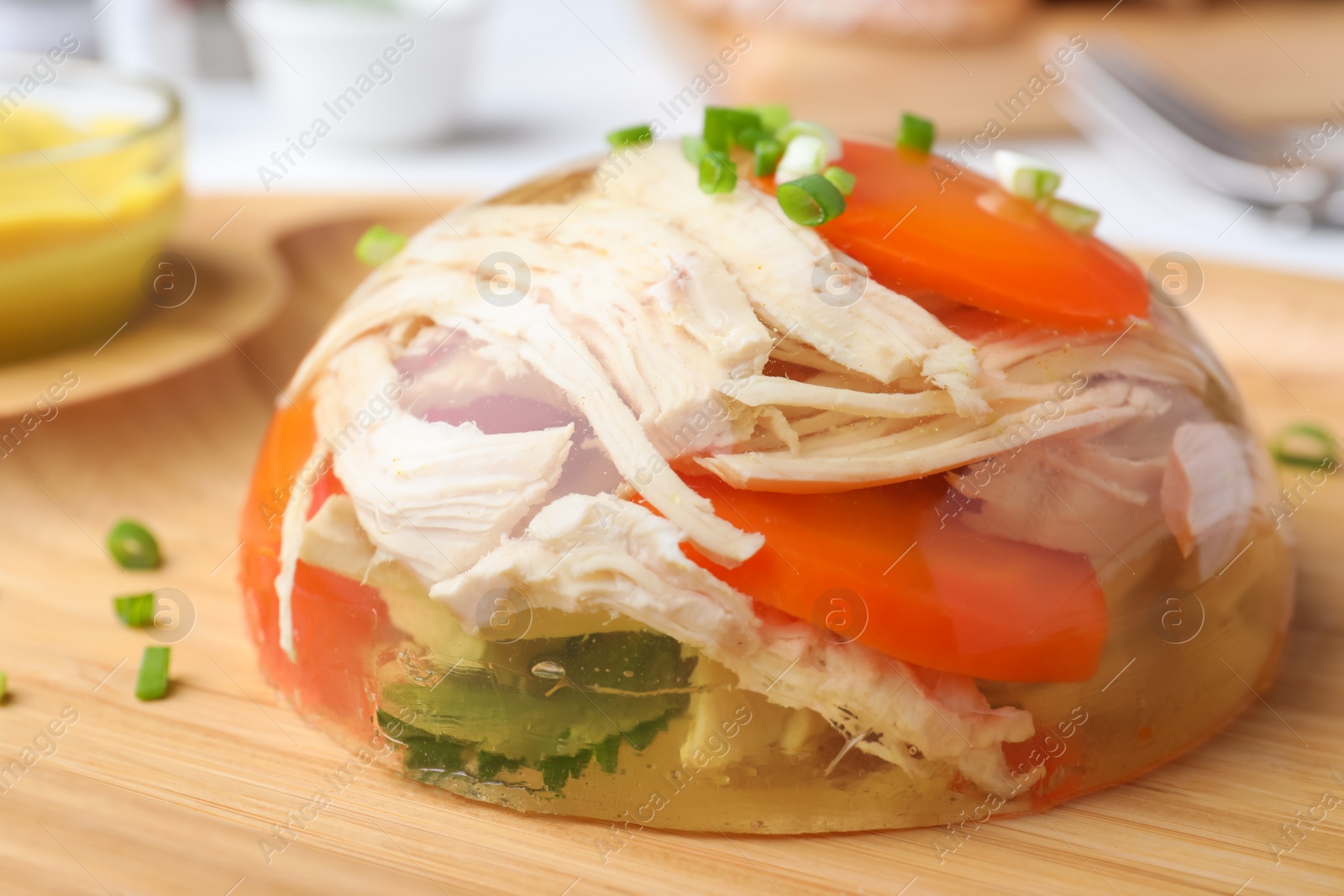 Photo of Delicious chicken aspic with vegetables on wooden plate, closeup