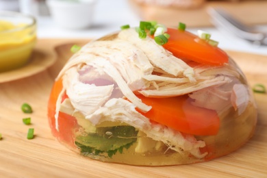 Delicious chicken aspic with vegetables on wooden plate, closeup