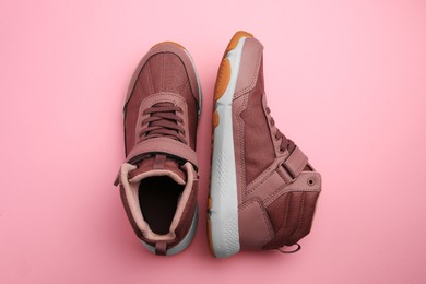 Photo of Pair of stylish kid's sneakers on pink background, top view