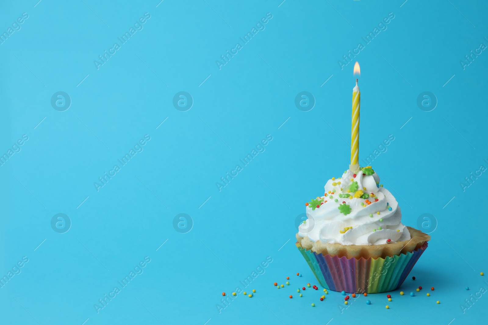 Photo of Birthday cupcake with candle on blue background, space for text. Greeting card